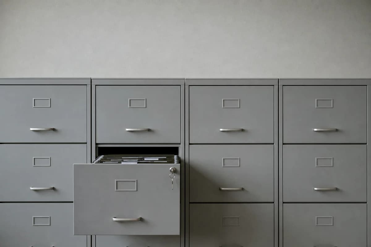 Article 32 asks whether your measures are appropriate to the risk. That is answered with evidence. A row of grey steel filing cabinets with one drawer open and a key left in the lock