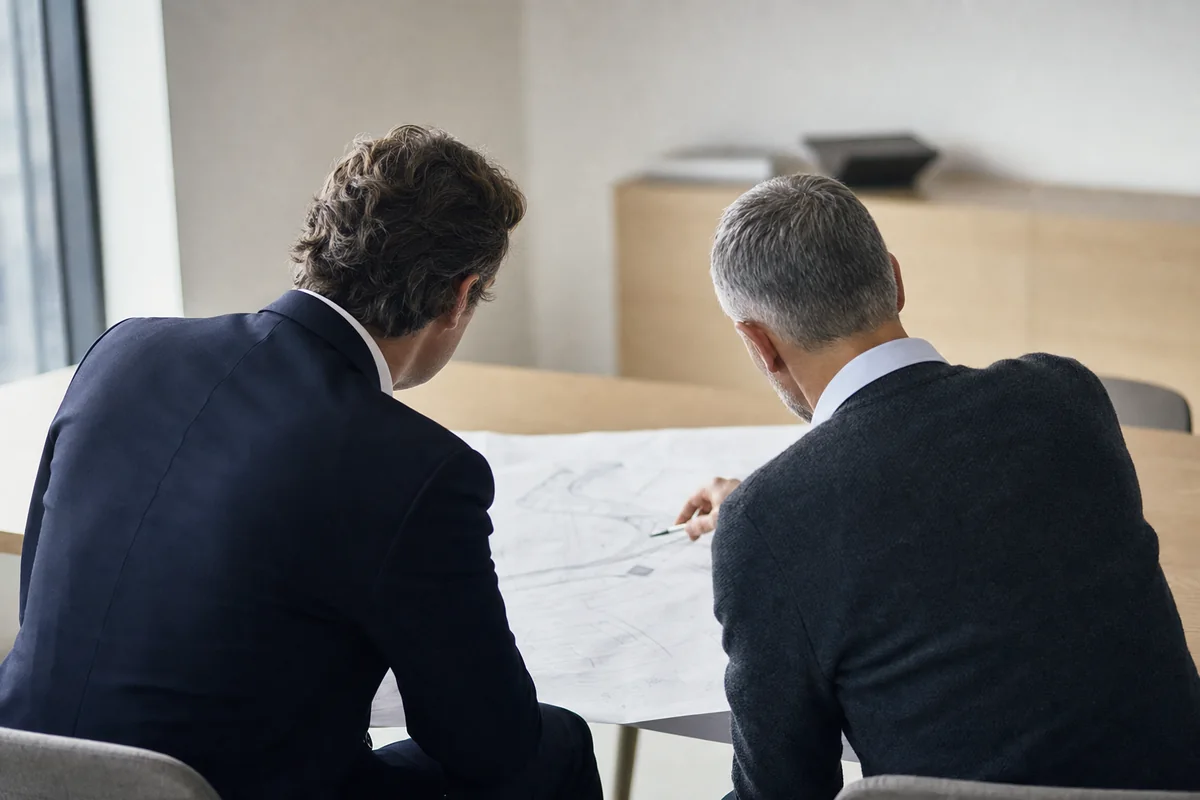 Gaps are closed with your engineers at the desk, not thrown over a wall as recommendations. A consultant and a client engineer working through a printed architecture diagram side by side