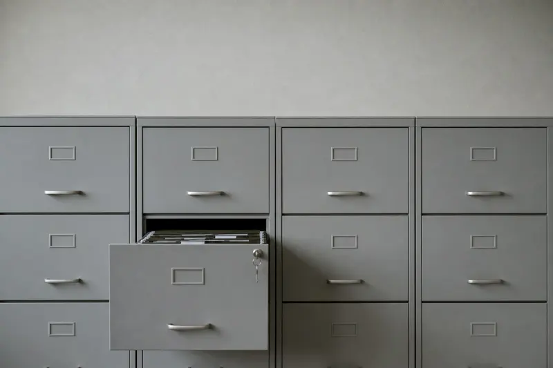 Article 32 asks whether your measures are appropriate to the risk. That is answered with evidence. A row of grey steel filing cabinets with one drawer open and a key left in the lock